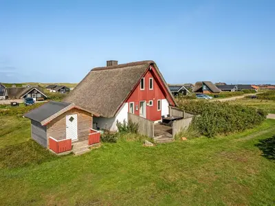 a red and white house on a green field at Holiday Home Iines - 200m from the sea by Interhome in Harboør