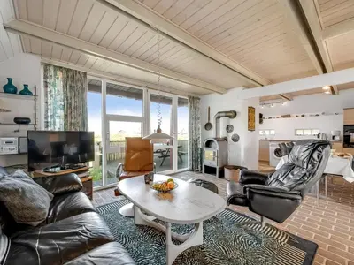 a living room with a couch and a table at Holiday Home Iines - 200m from the sea by Interhome in Harboør