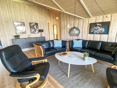 a living room with black leather furniture and a table at Holiday Home Filip - 100m from the sea by Interhome in Harboør