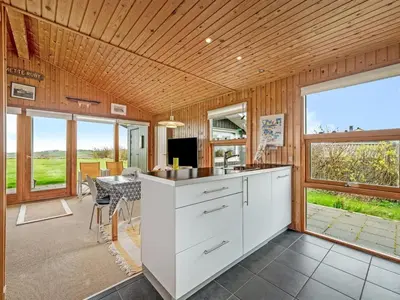 a kitchen with white cabinets and a dining room with a table at Holiday Home Tanea - 700m to the fjord by Interhome in Lemvig