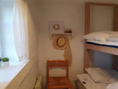 a bedroom with a chair and two bunk beds at Holiday Home Answald - 250m from the sea by Interhome in Harboør