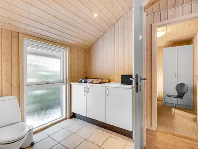 a bathroom with a toilet and a window at Holiday Home Elfrun - 250m from the sea by Interhome in Harboør