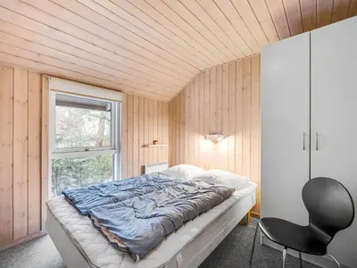 a bedroom with a bed and a chair and a window at Holiday Home Elfrun - 250m from the sea by Interhome in Harboør