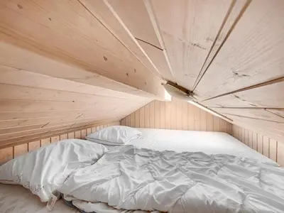 a bed in a room with a wooden ceiling at Holiday Home Elfrun - 250m from the sea by Interhome in Harboør
