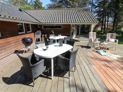 a patio with tables and chairs on a wooden deck at Holiday Home Elfrun - 250m from the sea by Interhome in Harboør