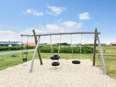 a swing set with three swings in the sand at Holiday Home Elfrun - 250m from the sea by Interhome in Harboør