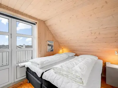 two beds in a room with a large window at Holiday Home Amandus - 100m from the sea by Interhome in Harboør