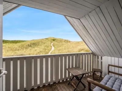 a porch with a chair and a table and a hill at Holiday Home Amandus - 100m from the sea by Interhome in Harboør