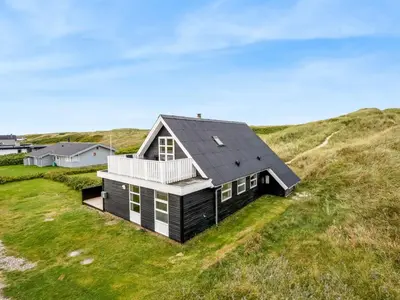 a black house on top of a grassy hill at Holiday Home Amandus - 100m from the sea by Interhome in Harboør