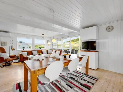 a living room with a wooden table and white chairs at Holiday Home Amandus - 100m from the sea by Interhome in Harboør