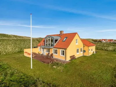 a yellow house with an orange roof in a field at Holiday Home Ali - 75m from the sea by Interhome in Harboør