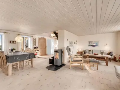 a living room with a fireplace and a table and chairs at Holiday Home Ali - 75m from the sea by Interhome in Harboør
