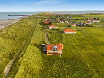 a group of houses on a grassy field next to the ocean at Holiday Home Ali - 75m from the sea by Interhome in Harboør