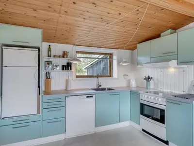 a kitchen with blue cabinets and a wooden ceiling at Holiday Home Suki - 650m from the sea by Interhome in Torsted