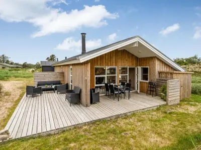 a wooden deck with chairs and tables on a house at Holiday Home Gyrial - 950m from the sea by Interhome in Torsted
