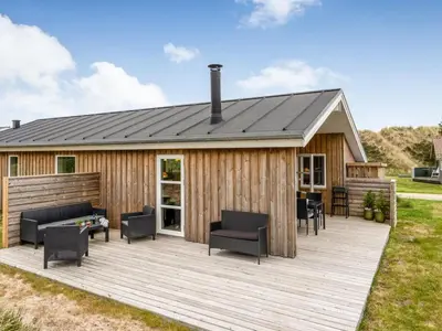 a wooden deck with chairs and a house at Holiday Home Gyrial - 950m from the sea by Interhome in Torsted