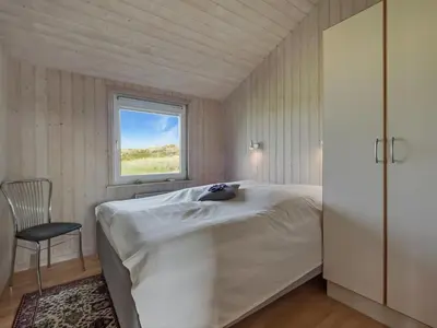 a bedroom with a bed and a window and a chair at Holiday Home Suometar - 400m from the sea by Interhome in Torsted