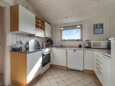 a large kitchen with white cabinets and a window at Holiday Home Suometar - 400m from the sea by Interhome in Torsted