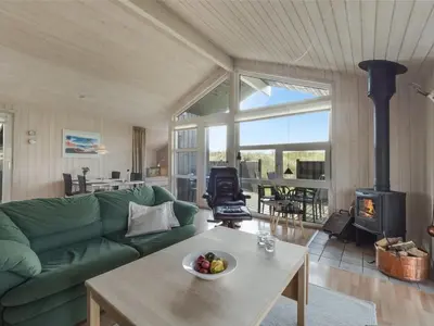 a living room with a green couch and a fireplace at Holiday Home Suometar - 400m from the sea by Interhome in Torsted