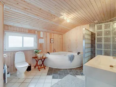 a bathroom with a tub and a toilet and a sink at Holiday Home Melanie - 950m from the sea by Interhome in Torsted