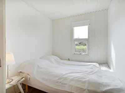 a white bedroom with a bed and a window at Holiday Home Vilja - 150m from the sea by Interhome in Torsted