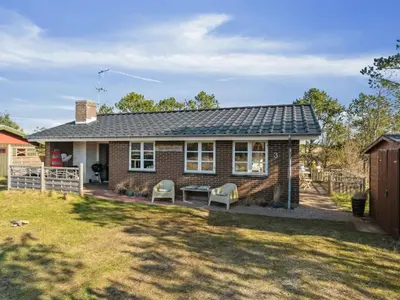 a small brick house with two chairs in a yard at Holiday Home Aurelie - 800m from the sea by Interhome in Torsted