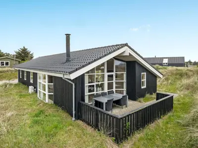 a black house on a grassy hill with a picnic table at Holiday Home Frido - 400m from the sea by Interhome in Torsted