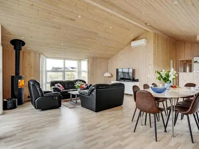 a living room with a table and chairs and a fireplace at Holiday Home Frido - 400m from the sea by Interhome in Torsted