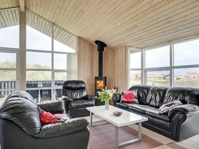 a living room with black leather couches and a table at Holiday Home Frido - 400m from the sea by Interhome in Torsted