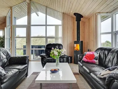 a living room with leather furniture and a fireplace at Holiday Home Frido - 400m from the sea by Interhome in Torsted
