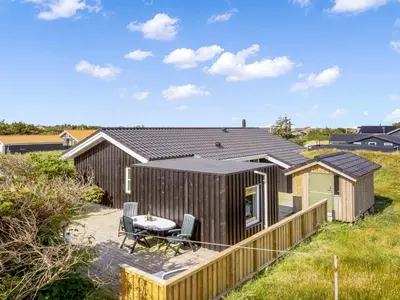 a tiny house with a patio and a table at Holiday Home Mauri - 350m from the sea by Interhome in Torsted