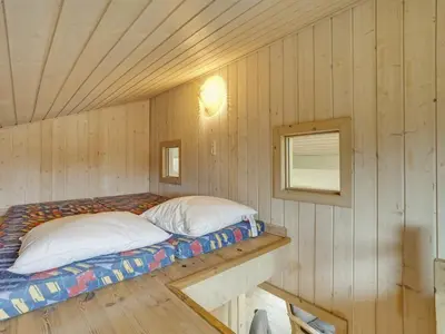 a bed in a room in a wooden cabin at Holiday Home Jerg - 500m from the sea by Interhome in Torsted