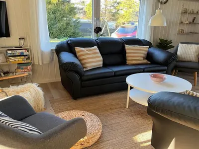 a living room with a black leather couch and a table at Holiday Home Styrmer - 1-2km from the sea by Interhome in Torsted