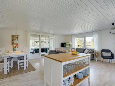 a kitchen and living room with a table and a couch at Holiday Home Styrmer - 1-2km from the sea by Interhome in Torsted