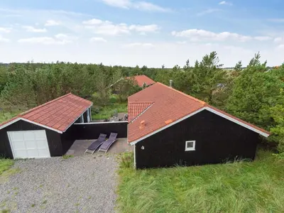 a black house with an orange roof on a field at Holiday Home Henkil - 700m from the sea by Interhome in Torsted