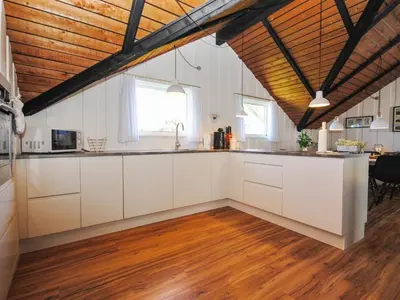 a kitchen with white cabinets and a wooden ceiling at Holiday Home Sakulf - 600m from the sea by Interhome in Torsted