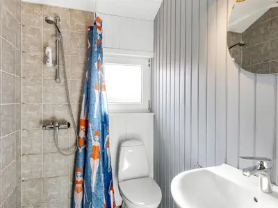 a bathroom with a shower curtain with a toilet and a sink at Holiday Home Antto - 900m from the sea by Interhome in Torsted