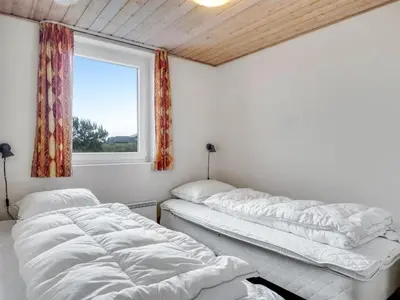 two beds in a room with a window at Holiday Home Palli - 600m from the sea by Interhome in Torsted