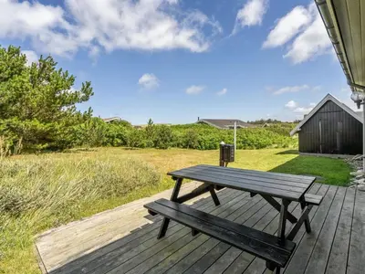 a wooden deck with a picnic table on it at Holiday Home Usko - 250m from the sea by Interhome in Torsted