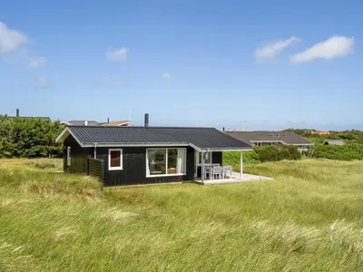 a black house sitting on top of a grassy field at Holiday Home Usko - 250m from the sea by Interhome in Torsted