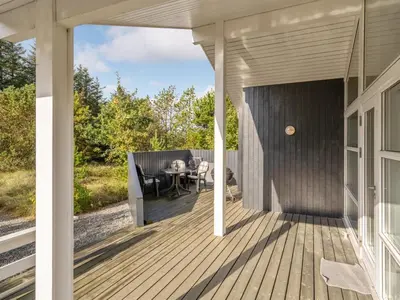 a deck with a table and chairs on a house at Holiday Home Alethe - 1km from the sea by Interhome in Torsted