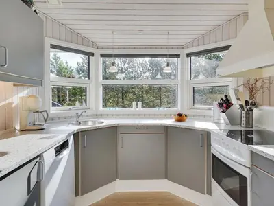 a kitchen with white counters and windows and a sink at Holiday Home Alethe - 1km from the sea by Interhome in Torsted