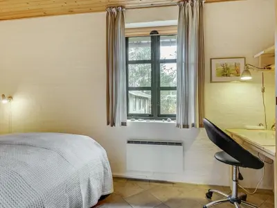 a bedroom with a bed and a desk and a window at Holiday Home Thermet - 900m from the sea by Interhome in Torsted