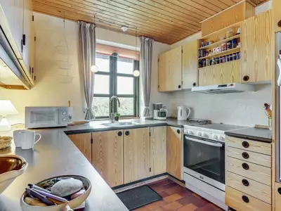 a kitchen with wooden cabinets and a stove at Holiday Home Thermet - 900m from the sea by Interhome in Torsted
