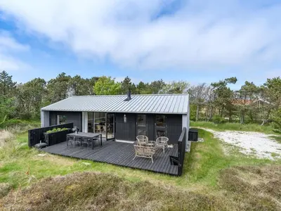 a black tiny house with a deck on a field at Holiday Home Fidelia - 800m from the sea by Interhome in Torsted