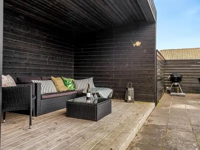 a patio with a couch and a table and a grill at Holiday Home Pontus - 400m from the sea by Interhome in Torsted