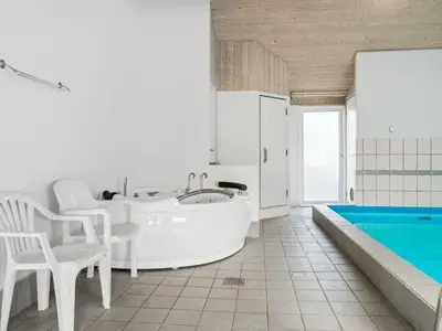 a white bathroom with a tub and a table and chairs at Holiday Home Zoya - 900m from the sea by Interhome in Torsted