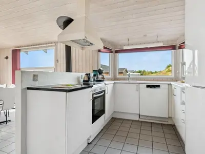 a kitchen with white cabinets and a large window at Holiday Home Zoya - 900m from the sea by Interhome in Torsted