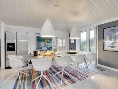 a dining room with a table and white chairs at Holiday Home Fris - 100m from the sea by Interhome in Torsted