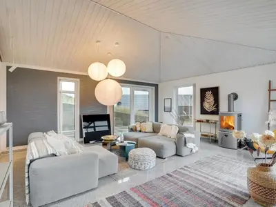 a living room with white furniture and a fireplace at Holiday Home Fris - 100m from the sea by Interhome in Torsted